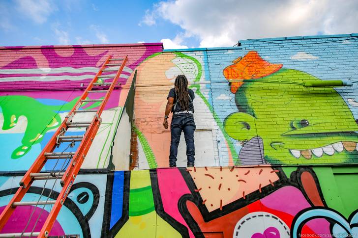 A photo of a woman painting a mural in Bushwick